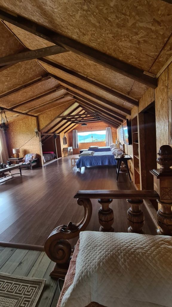 Quarto com vigas de madeira e janela para a serra
